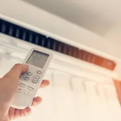 Mano ajustando el control remoto del aire acondicionado para mantener la temperatura ideal. Control de calefacción y refrigeración.