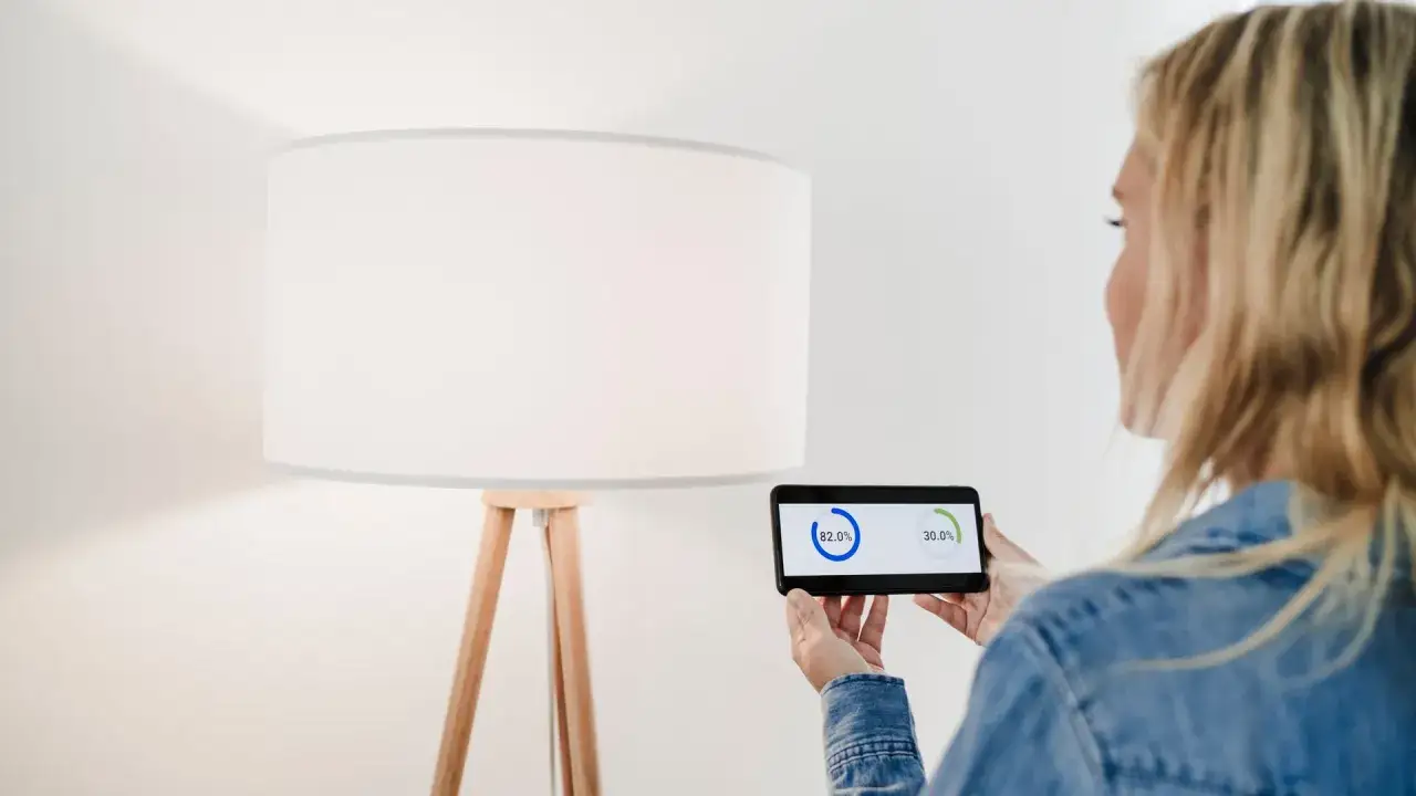 Mujer controla lámpara con su móvil, aprendiendo como domotizar tu casa con Alexa.