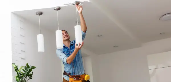 Hombre instalando una lámpara de techo. Aprende como cambiar una lámpara de techo fácilmente.